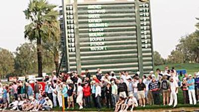 Spectators watch from in front of the leaderboard during the Dubai play-off between Miguel Angel Jimenez and Lee Westwood.