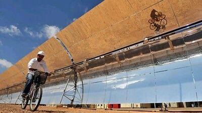 An engineer cycles past solar panels at the Ain Beni Mathar solar power station. Morocco has ambitions of exporting solar power to Europe. ABDELHAK SENNA / AFP
