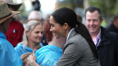 Meghan is embraced by a local woman during a visit to a community picnic at Victoria Park in Dubbo, Australia. AP
