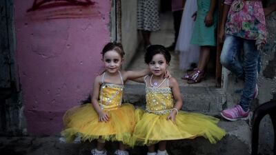 Two girls pose for a picture as they sit in front of the family house during the wedding party of Palestinian groom Saed Abu Aser.
