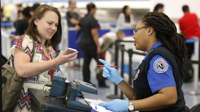 A TSA officer with a traveller at Miami airport. Border guards are increasingly pressing travellers to open up devices. Wilfredo Lee / AP Photo
