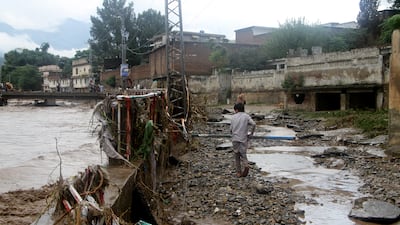 A boy clears debris next to the Swat river. EPA