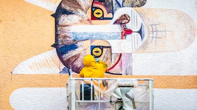 An artist paints a mural on a building in Zurich, Switzerland. EPA