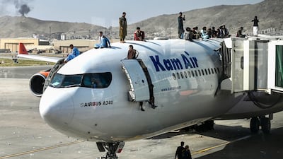 Afghans desperate to flee the Taliban climb on top of a Kam Air plane at Kabul airport on August 16, 2021. AFP