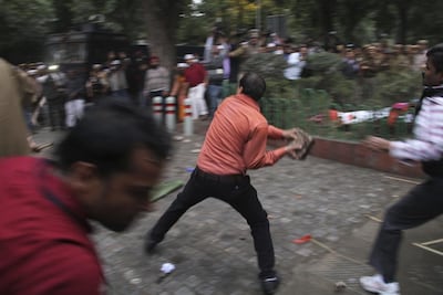 A BJP supporter throws rocks at supporters of Aam Aadmi Party outside the BJP office in New Delhi. AP