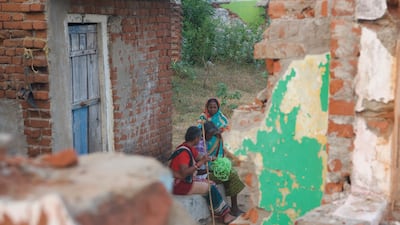 Former inhabitants of the of Podemepta village sit at an abandoned house. The houses once belonged to a prosperous fishermen community but are now a testimony of widespread devastation caused by climate change.