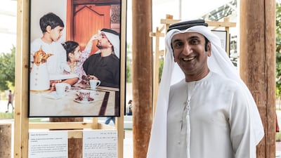 Issam Al Mulla stands next to the picture of him and his children at the exhibition.
