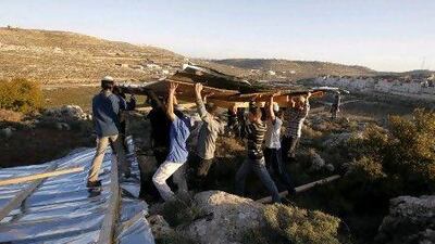 Jewish settlers carry planks as they build a makeshift structure at the unauthorised outpost of Mitzpe Avihainear the West Bank city of Hebron