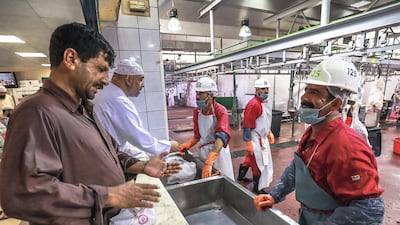 A customer instructs a slaughter house worker on the type of cuts he wants for his meat.