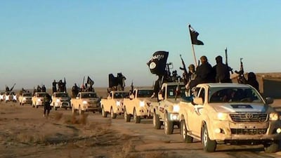 ISIL militants hold up their weapons and wave flags as they ride in a convoy, which includes multiple Toyota pickup trucks, through Raqqa city. AP