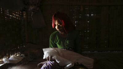 Gorima Khatu holds the covered body of her three-month-old daughter Asoma Khatu, who just died of fever and diarrhoea, in their room at the Kyein Ni Pyin camp.