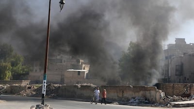 Men walk past burning tyres, which activists say are being used to create smoke cover from warplanes, in a rebel-held neighbourhood of Aleppo on July 31, 2016. Abdalrhman Ismail/Reuters