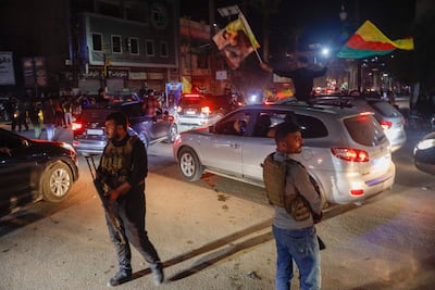 Syrian Democratic Forces fighters stand guard as residents celebrate the signing of the agreement, in Qamishli. AP