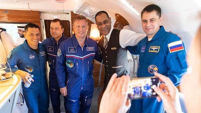 Nasa astronauts and Russian cosmonauts pose for a photo with an Emirates employee