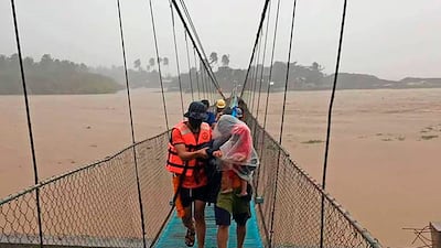 Rescuers help residents cross a bridge to safety in Tubay town, Agusan del Norte, southern Philippines. Photo: AP Photo