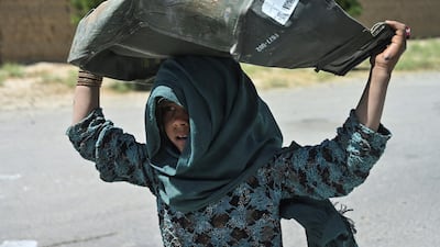 A girl carries a metal box she collected from a junkyard near the Bagram Air Base. AFP