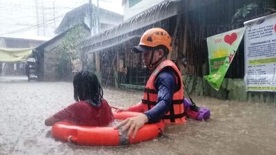 A Philippine Coast Guard helps a resident in Typhoon Rai in Cagayan De Oro. Photo: Reuters