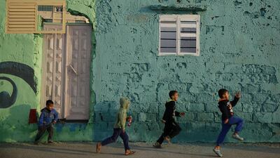 Palestinian boys run past a painted house. Shati has always been a symbol of poverty, a grey concrete jungle with 87,000 people packed into about half a square kilometre.