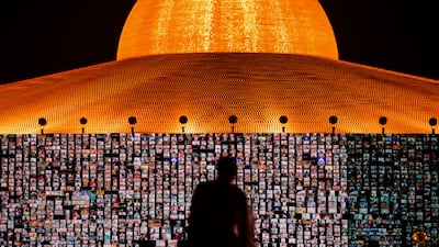 People pray as screens show devotees gathering via Zoom during a ceremony to commemorate the Buddhist Lent Day in Pathum Thani province, Thailand.