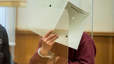 Former Syrian secret police officer Eyad Al Gharib covers his face from reporters as he faces trial in Germany for crimes committed in Syria, on February 24, 2021. Reuters