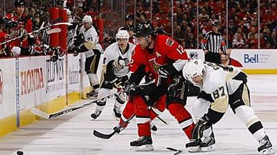 Mike Fisher, #12, of the Ottawa Senators tries to control the puck along the boards while battling with Penguins captain Sidney Crosby.