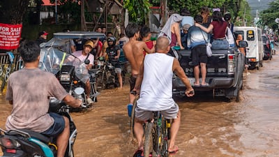 Residents wade through ankle-deep floodwaters in Barangay Gitnang Bayan I, San Mateo, Rizal. AFP