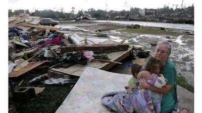 Faye Hyde sits in what was her yard as she comforts her granddaughter Sierra Goldsmith, 2, in Concord, Alabama.