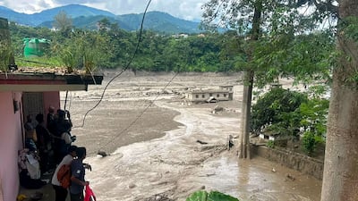 Residents watch a torrent of muddy water surge through their town. AFP