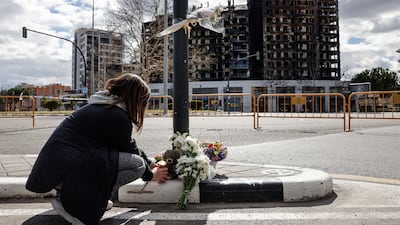 A woman lays flowers near the apartment block in Valencia, Spain, where at least 10 people died in a fire. EPA