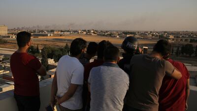 Local people surround a media member as they observe a smoke rising above the Syrian border town of Tel Abyad, as seen from Akcakale, Turkey. Reuters