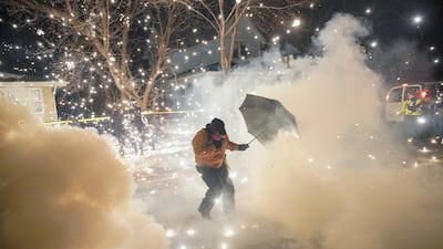 A protester uses an umbrella for cover from projectiles fired by federal agents, in north Minneapolis, Minnesota. Reuters