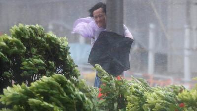A man holds onto a lamp post against strong wind as Typhoon Hato hits Hong Kong. Tyrone Siu / Reuters.