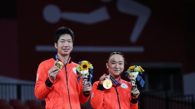 Jun Mizutani, left, and Mima Ito of Japan on the podium with their gold medals after defeating China team at the mixed doubles gold medal table tennis match.