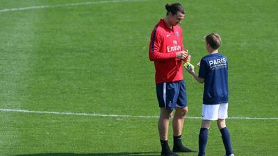 TOPSHOT - Paris Saint-Germain's Swedish striker Zlatan Ibrahimovic (L) speaks with a boy from the Paris Saint-Germain Academy during a training camp in the Qatari capital Doha, on December 28, 2015. AFP PHOTO / KARIM JAAFAR / AFP / KARIM JAAFAR