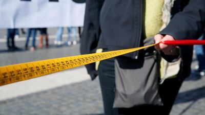 A person holds a measuring tape during the protest against war in Syria, keeping one metre distance at St. Peter's Square. Reuters
