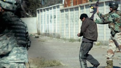A US soldier, left, stands to the left as a handcuffed suspect is kicked, punched and struck with a rifle butt by Iraqi soldiers.