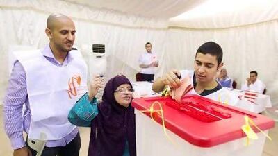 The Dubai polling station manager Khalid Hijazi watches as Najwa Mohamed, 76, places her vote in the ballot box with the help of Ezeddean Hassan yesterday.