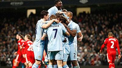 City's Yaya Toure, obscured, celebrates with teammates including his brother Kolo Toure, top, after scoring against Liverpool.