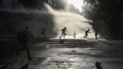 Anti-government protesters run amid the spray of a police water cannon during demonstrations against economic inequality in Santiago, Chile. AP Photo