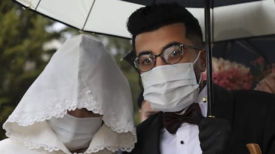 Palestinian groom Imad Sharaf, wearing gloves and a face mask, accompanies his bride Bara'a Amarneh as they arrive at their home in the village of al-Dahriya, south of Hebron in the West Bank. AFP