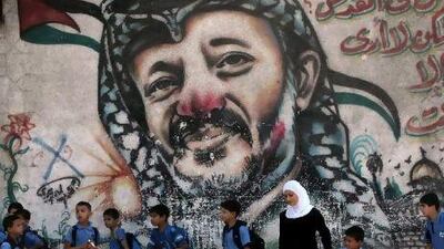 Palestinian schoolchildren stand with a woman in front of a painting of the late Palestinian leader, Yasser Arafat, in central Gaza yesterday. Mahmud Hams /AFP
