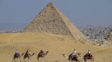 Tourists ride camels past the Giza Pyramids necropolis, in Egypt. AFP
