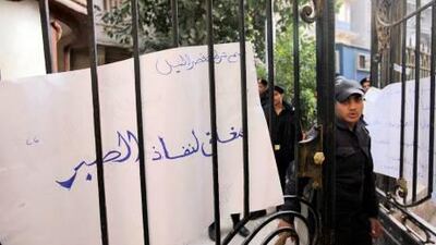 An Egyptian policeman on strike stands at the gate of the Qasr el-Nile police station, in front of a banner that reads: "Closed for the end of our patience," during a protest in Cairo this month. Amr Nabil / AP Photo