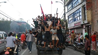 Protesters carry Nepal's national flag as they ride a police truck outside the President House. AFP