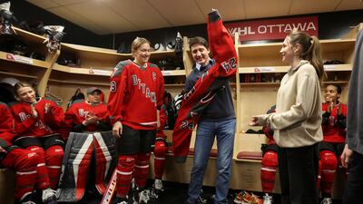 Canada's Prime Minister Justin Trudeau puts on an Ottawa ice hockey team jersey as he meets players before their game against Boston in Ontario. Reuters