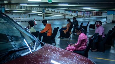 People who were inoculated sit under observation during a drive in facility for Covid-19 vaccination at a car parking area of a shopping mall in Kochi, Kerala state, India. AP