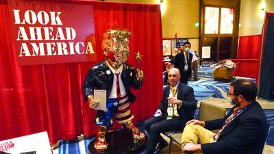 Conservative figure Matt Braynard, left, talks to conference attendees next to the golden statue of former president Donald Trump, at the Conservative Political Action Conference. AP Photo