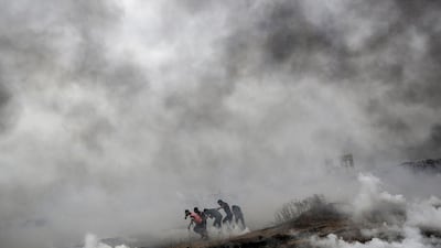 Palestinian medics help protesters after Israeli troops fired tear-gas during clashes after Friday protests near the border with Israel in eastern Gaza City. Mohammed Saber / EPA
