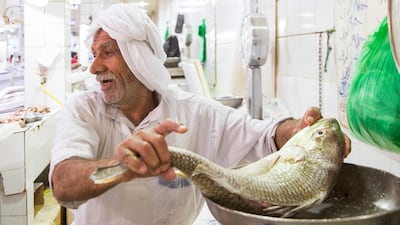 A vendor weighs a fish at Kuwait City's fish market, which has remained stocked despite supply disruptions caused by the Iran war. Photo: Kim Steele