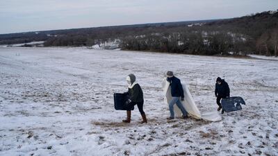 A group climbs a steep, snow-covered hill next to Lake Waco dam in Texas. AFP